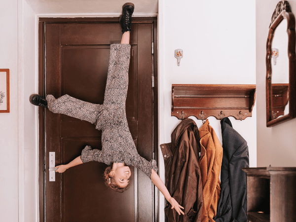 Meisje staat op de kop bij de voordeur.