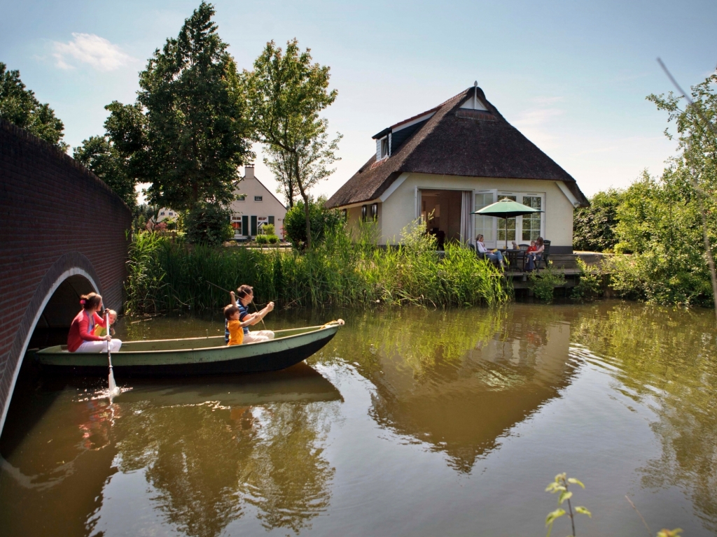 Vakantie huisje langs een kanaal met een kano erin.