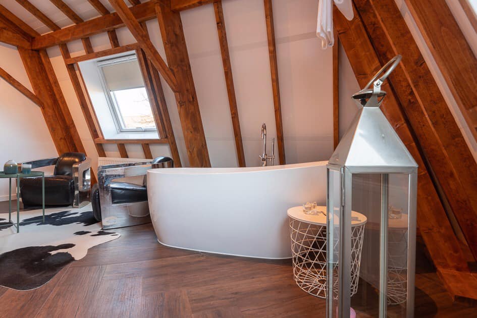 Gezellig knus ingerichte kamer met een bad in de woonkamer.